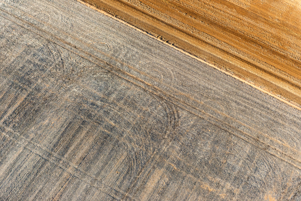 Diagonal aerial view of contrasting harvested paddocks, highlighting patterns in soil - Australian Stock Image