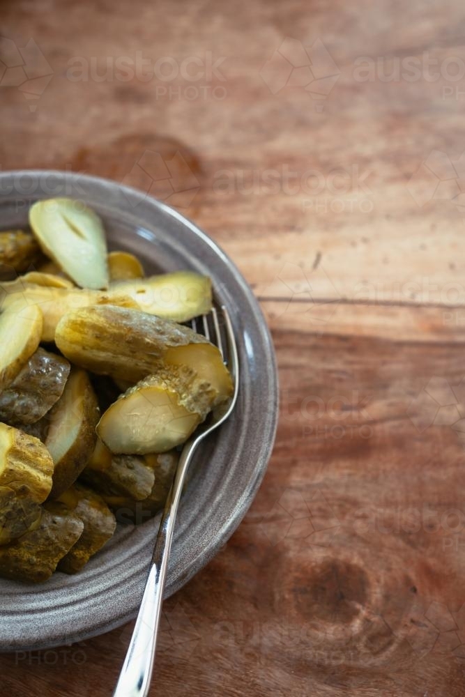 dill pickles in an earthenware bowl with fork - Australian Stock Image