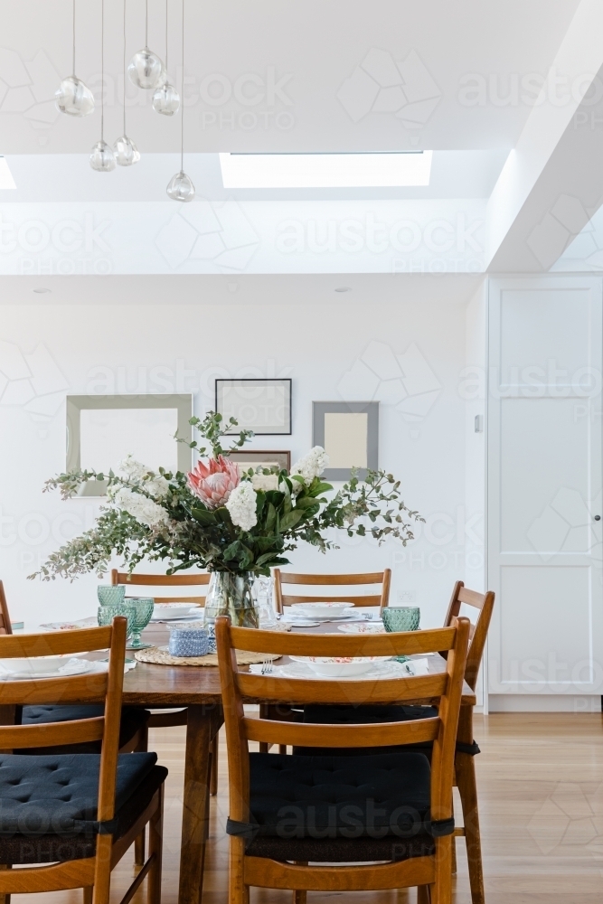 Dining table set for lunch with a large floral center piece - Australian Stock Image