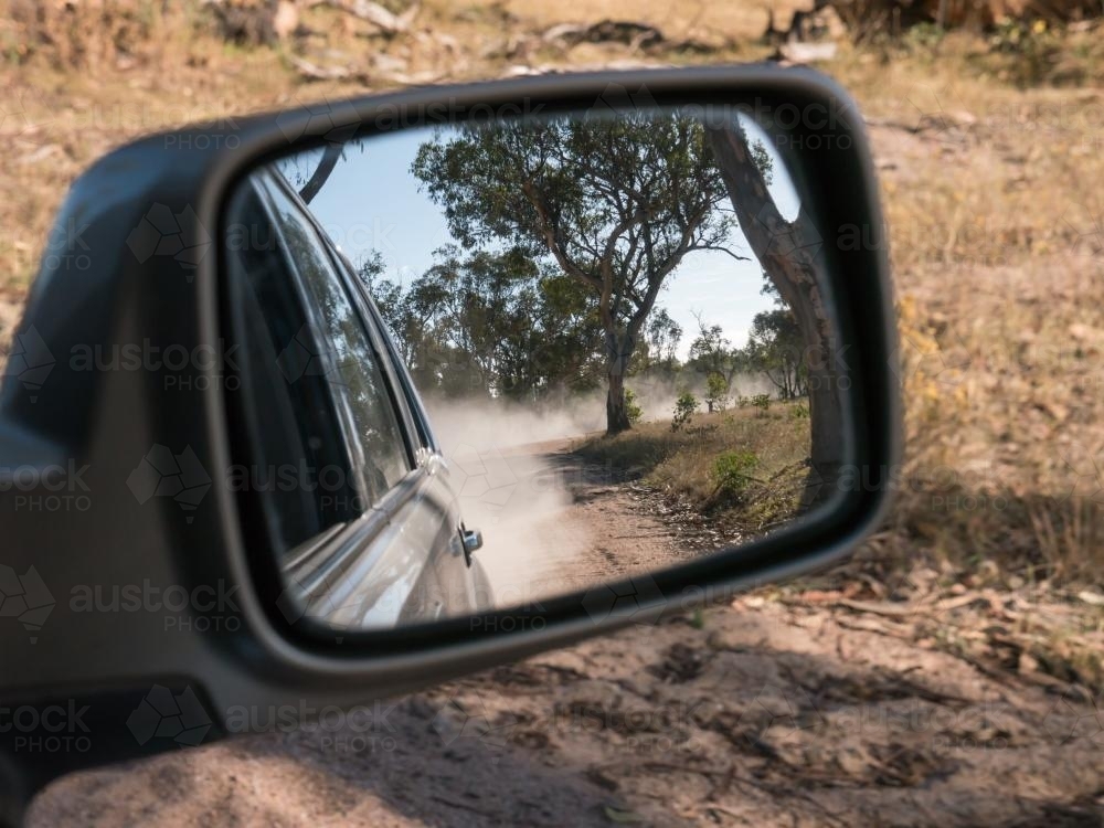 Dirt road and dust in the rear vision mirror of a car - Australian Stock Image