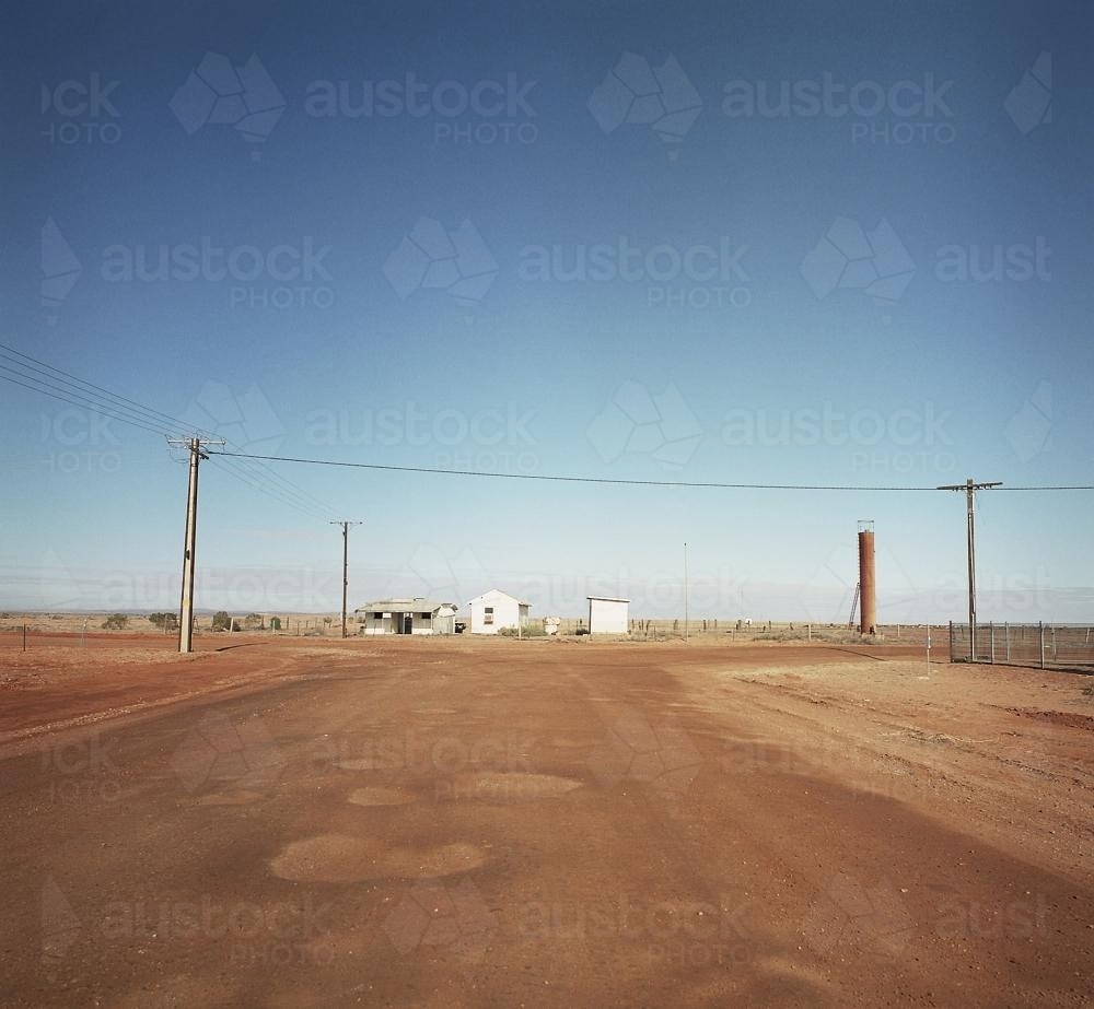 Dirt road in remote town with houses and power lines - Australian Stock Image