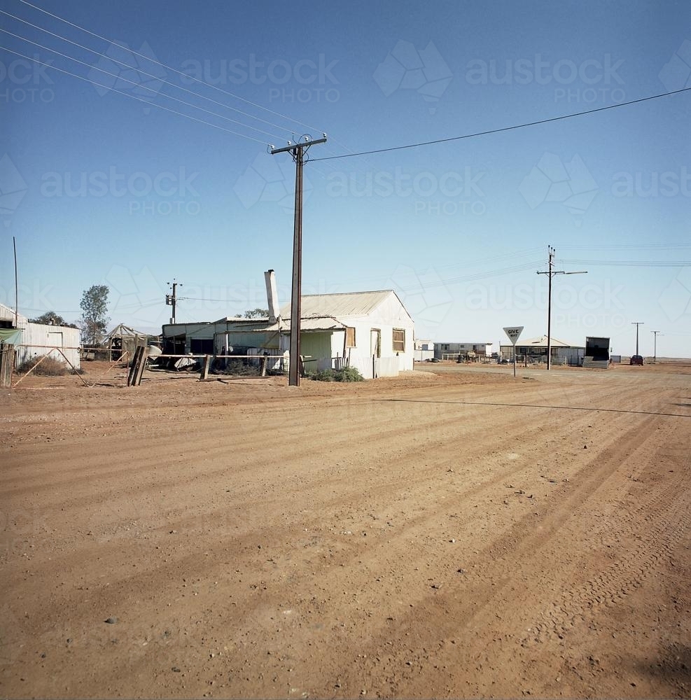 Dirt road in remote town with power lines and old house - Australian Stock Image