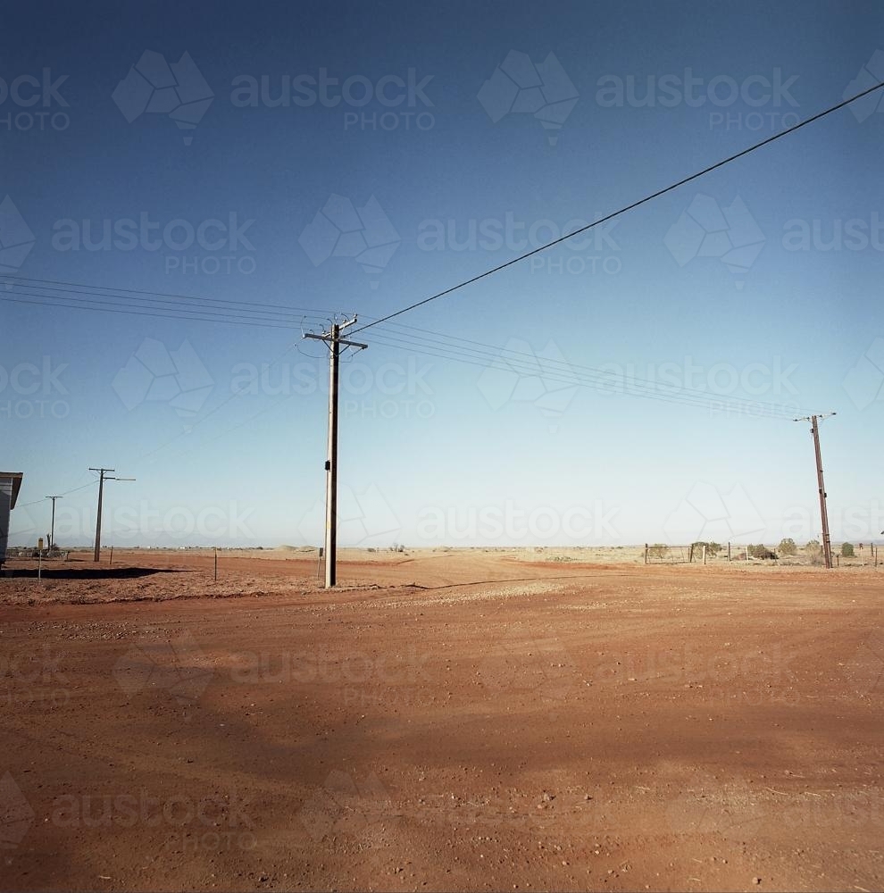 Dirt road in remote town with power lines - Australian Stock Image