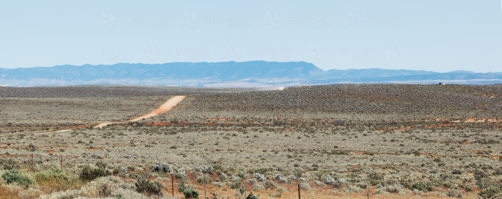 dirt road through plains going towards hills - Australian Stock Image