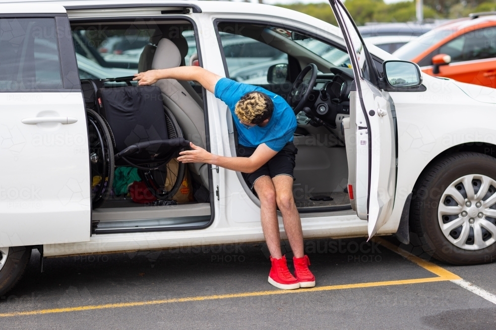 Image of disabled driver putting wheelchair into car Austockphoto