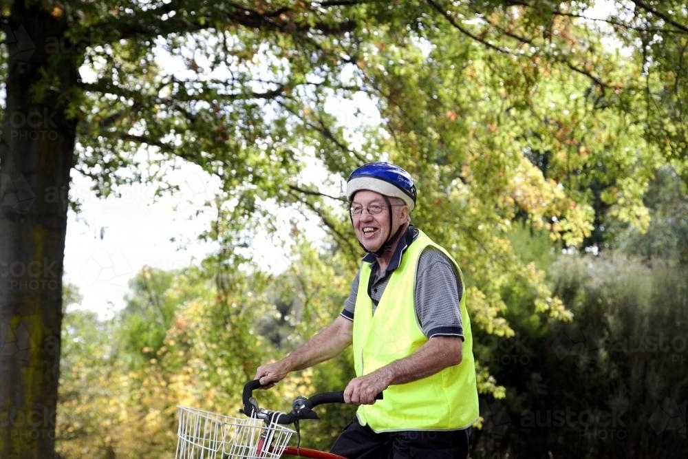 Disabled man in high visibility vest riding bike - Australian Stock Image