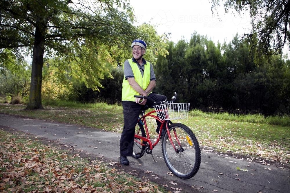 Disabled man in high visibility vest sitting on bike - Australian Stock Image