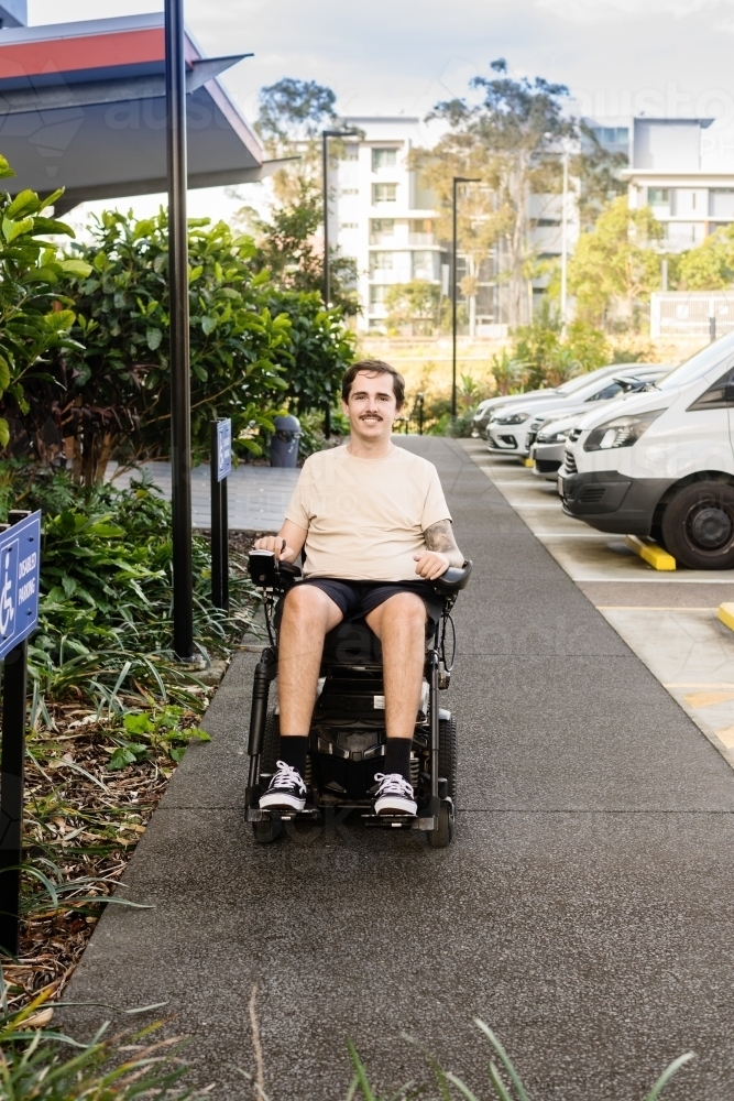 disabled man in motorised wheelchair, in carpark - Australian Stock Image