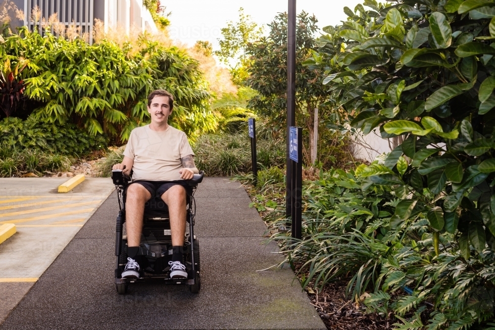 disabled man in motorised wheelchair, in carpark - Australian Stock Image