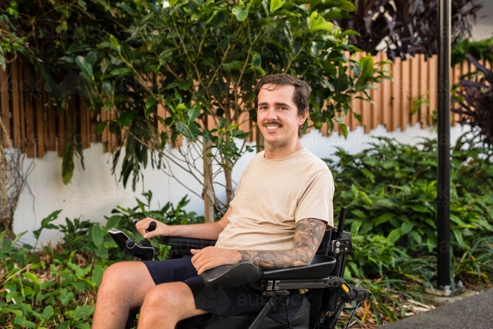disabled man in motorised wheelchair, in carpark - Australian Stock Image