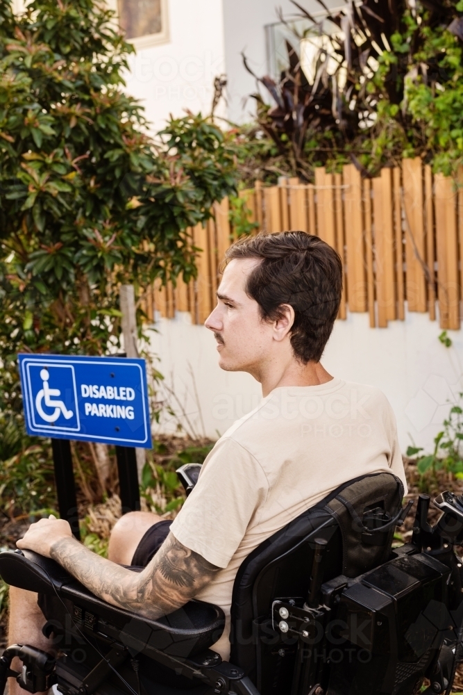 disabled man in motorised wheelchair, in carpark - Australian Stock Image