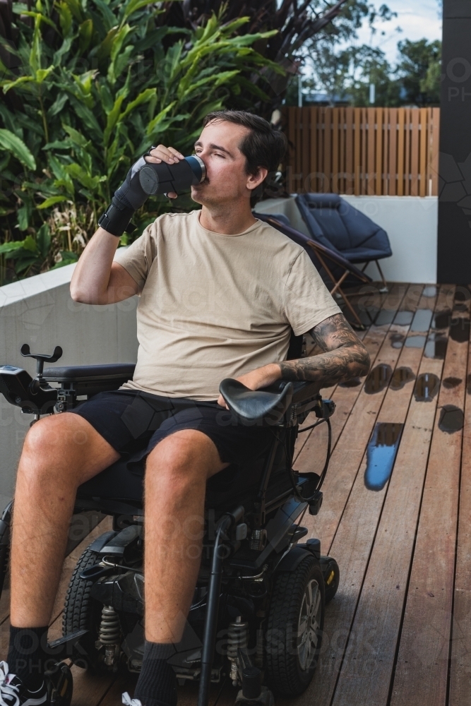 disabled man with custom made drinking cup - Australian Stock Image