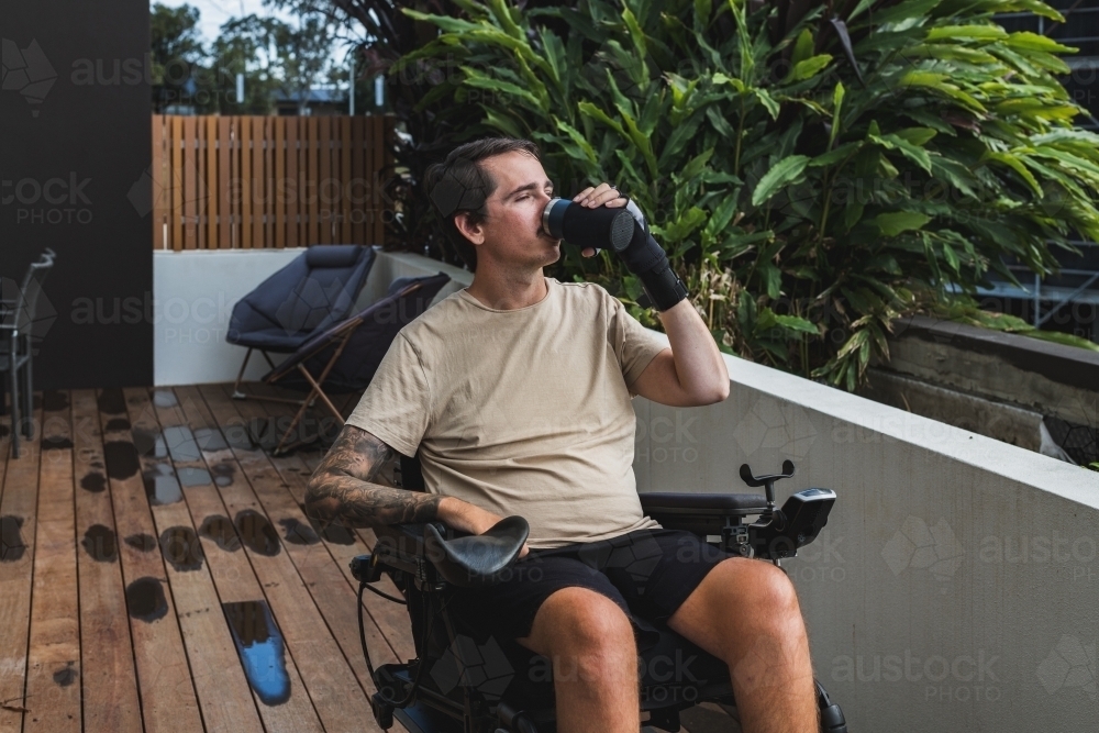 disabled man with custom made glove for drinking - Australian Stock Image