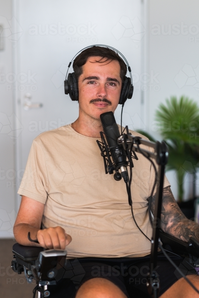 disabled podcaster with microphone and headphones - Australian Stock Image