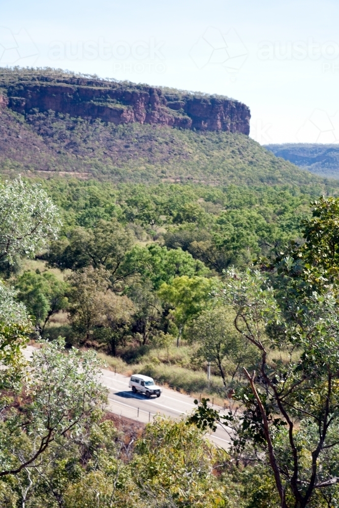 Distant car driving along road in bushland - Australian Stock Image