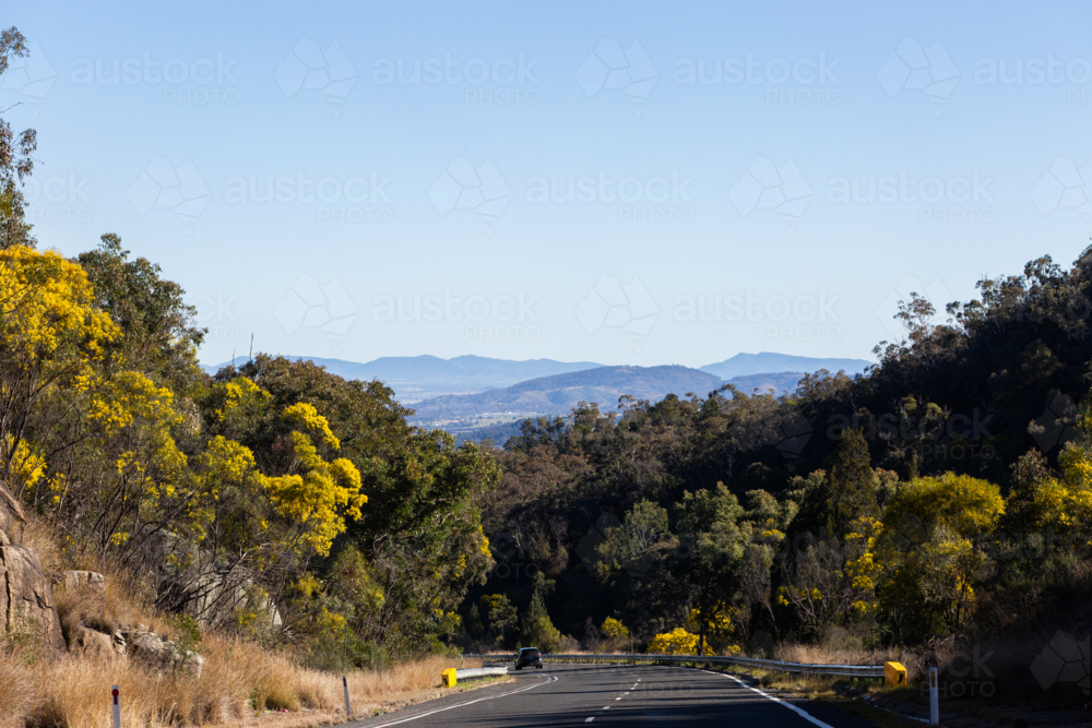 Distant car traveling down highway on road trip adventure through Australia in late winter - Australian Stock Image