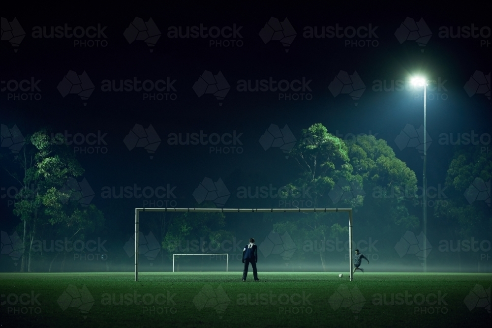 Distant people playing sport in fog at night - Australian Stock Image