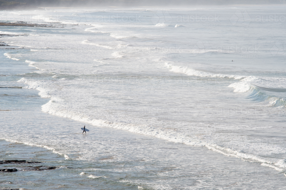 Distant surfer entering the surf - Australian Stock Image