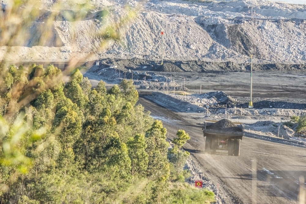 Distant truck carting coal in open cut mine - Australian Stock Image