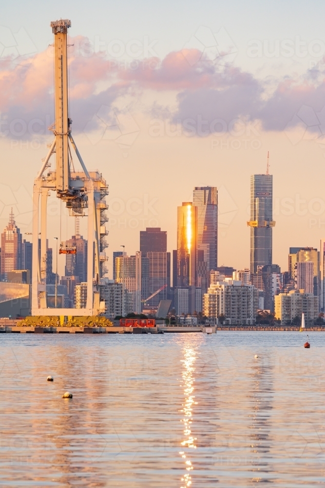 Distant view of a large gantry crane in front of high rise buildings, all reflected in calm water - Australian Stock Image