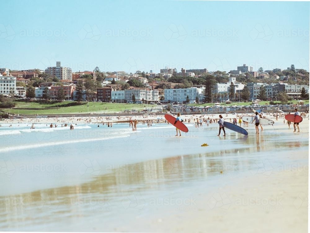 Distant view of people entering the water with long boards on Bondi Beach - Australian Stock Image