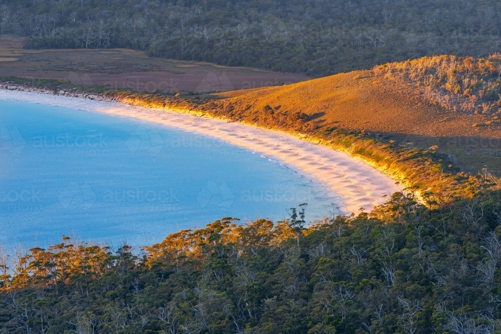 Distant view of Wine Glass Bay in early morning sunshine - Australian Stock Image