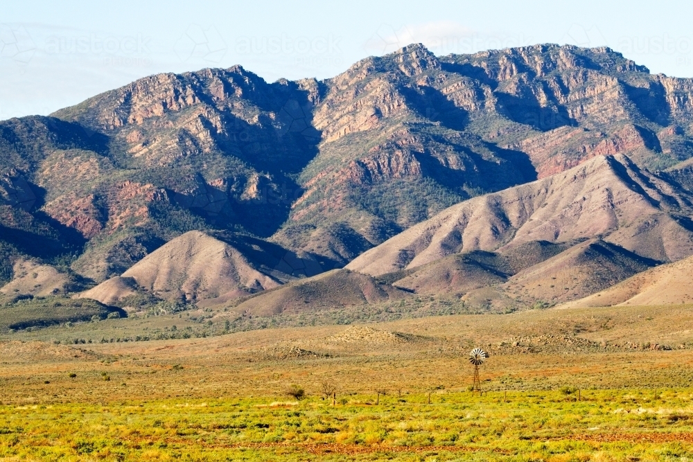 Distant windmill in front of rugged ranges, horizontal - Australian Stock Image