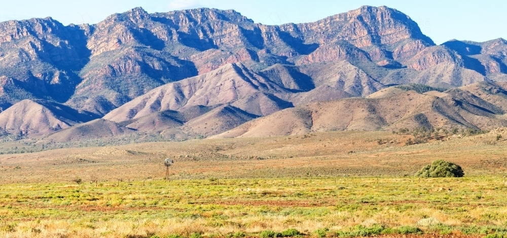 Distant windmill in front of rugged ranges, panoramic - Australian Stock Image