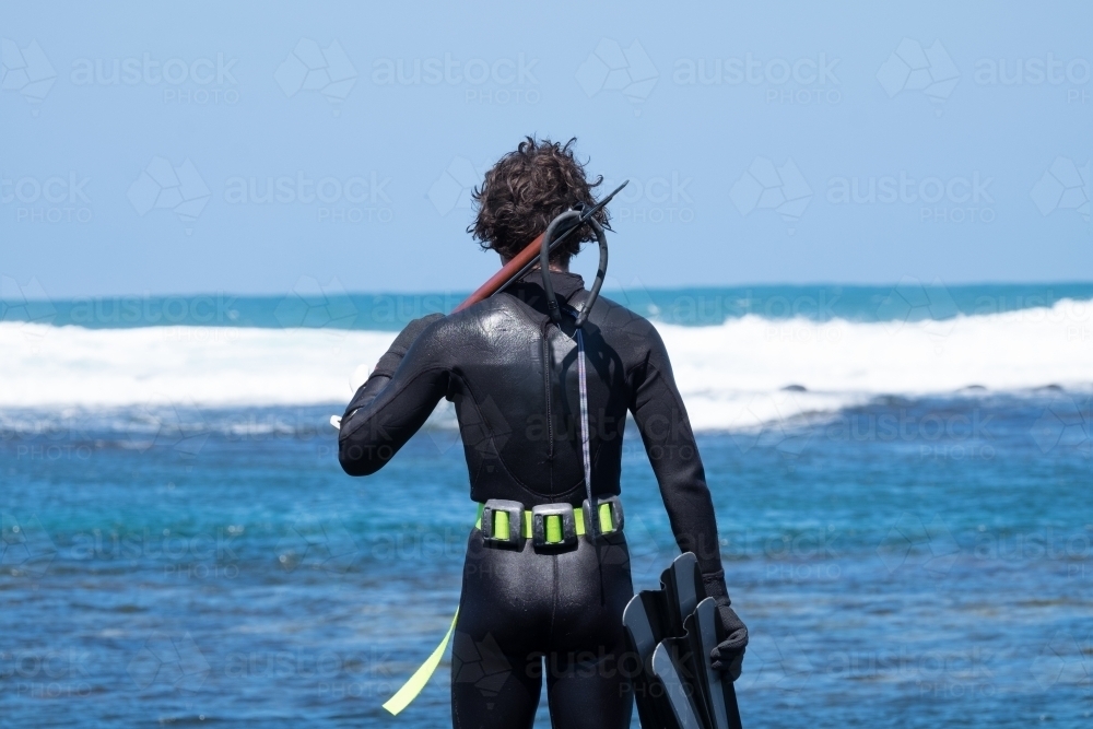 Diver looks out to sea with his spear gun. - Australian Stock Image