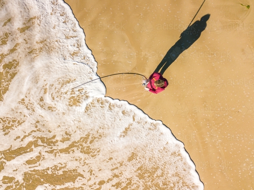 Aerial view of a fisherman and waves on a beach - Australian Stock Image