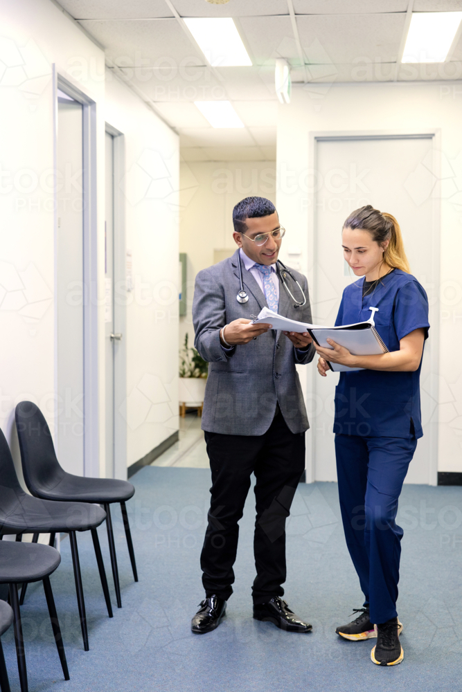 Doctor and nurse talking while walking on the hallway - Australian Stock Image