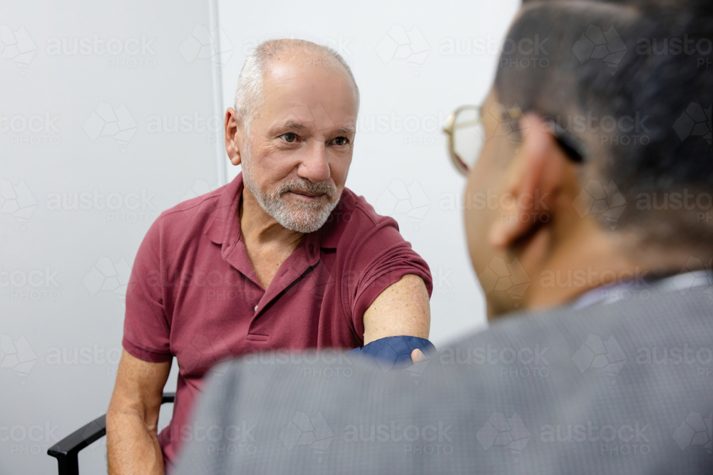 Doctor checking senior mans blood pressure - Australian Stock Image