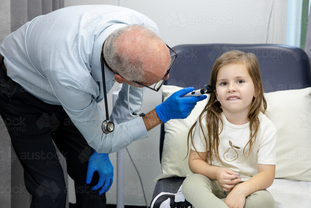 Doctor checking young girls ear with otoscope - Australian Stock Image