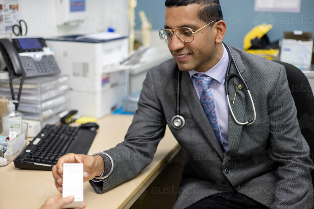 Doctor handing prescription medicine to female patient - Australian Stock Image