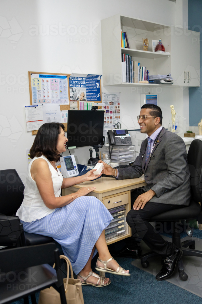 Doctor handing prescription medicine to female patient - Australian Stock Image