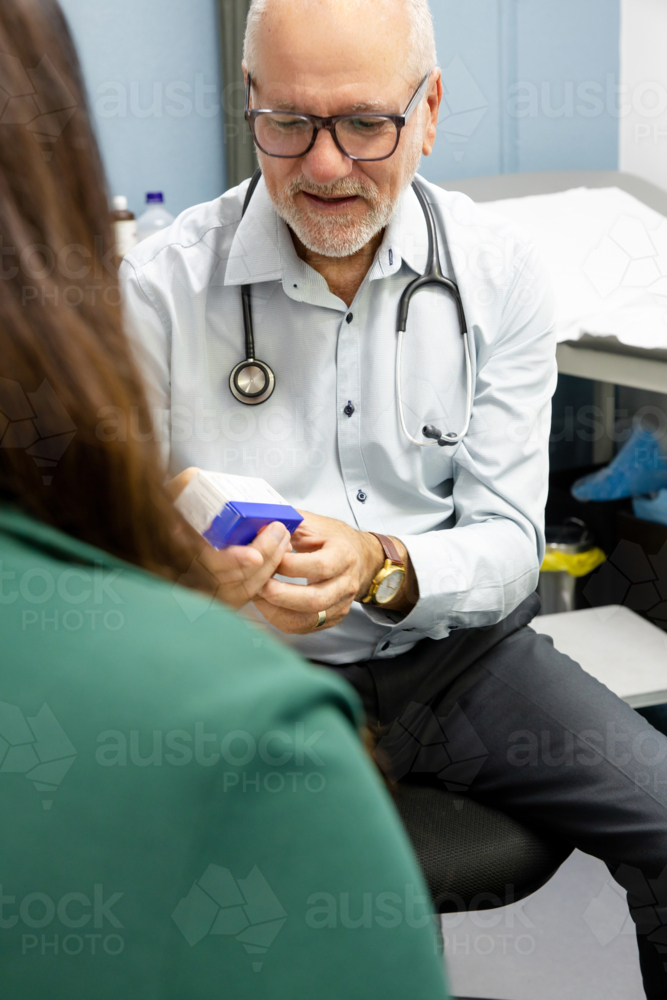 Doctor holding a medicine box showing it to patients - Australian Stock Image