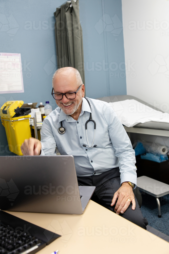 Doctor in office working at laptop - Australian Stock Image