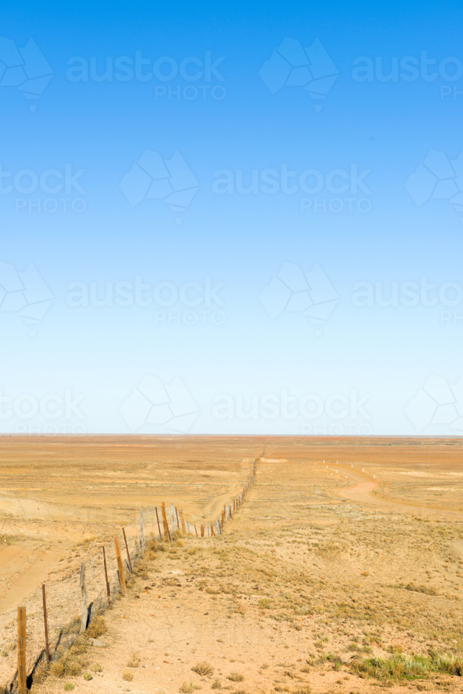 Dog fence stretching into the distance across arid outback land - Australian Stock Image