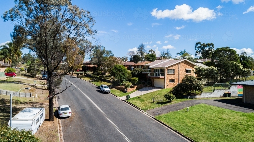 Double lines on road of suburban area with houses and parked cars - Australian Stock Image