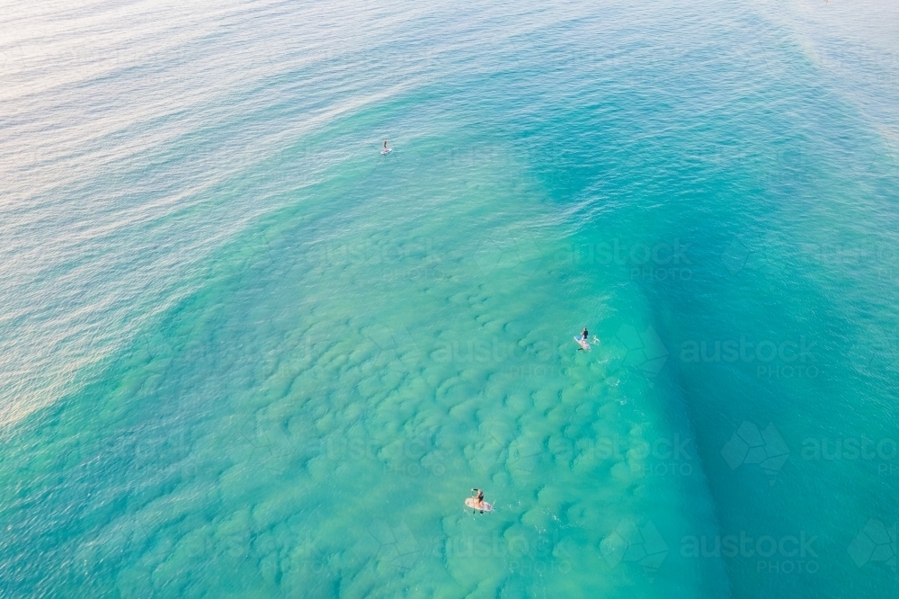 Down below with the blue sea water and a few people paddle boarding - Australian Stock Image