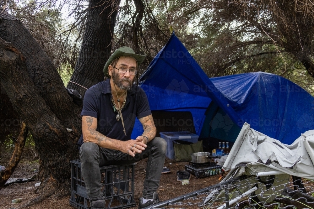 down on his luck - homeless man at his urban camp among bushes - Australian Stock Image