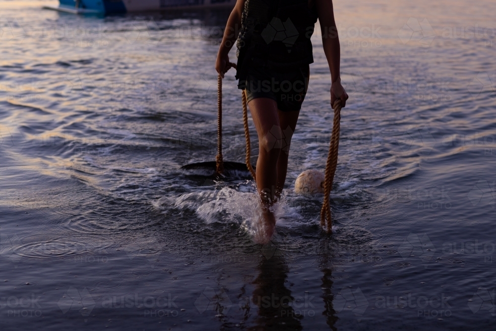 dragging anchor out of water at dusk after boating all day - Australian Stock Image