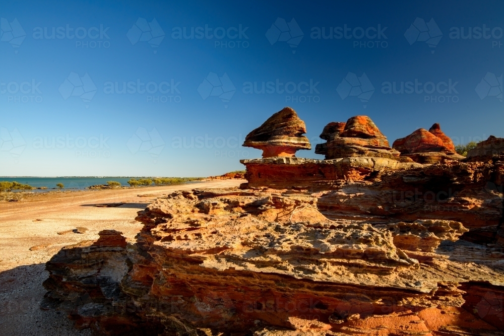 Dramatic and unusual orange rock formations on a bayside beach - Australian Stock Image