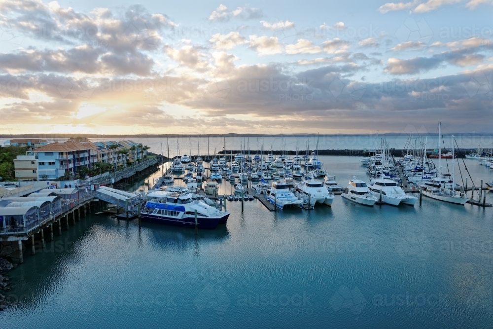 Dramatic clouds at dawn catching the light on the water Hervey Bay marina - Australian Stock Image