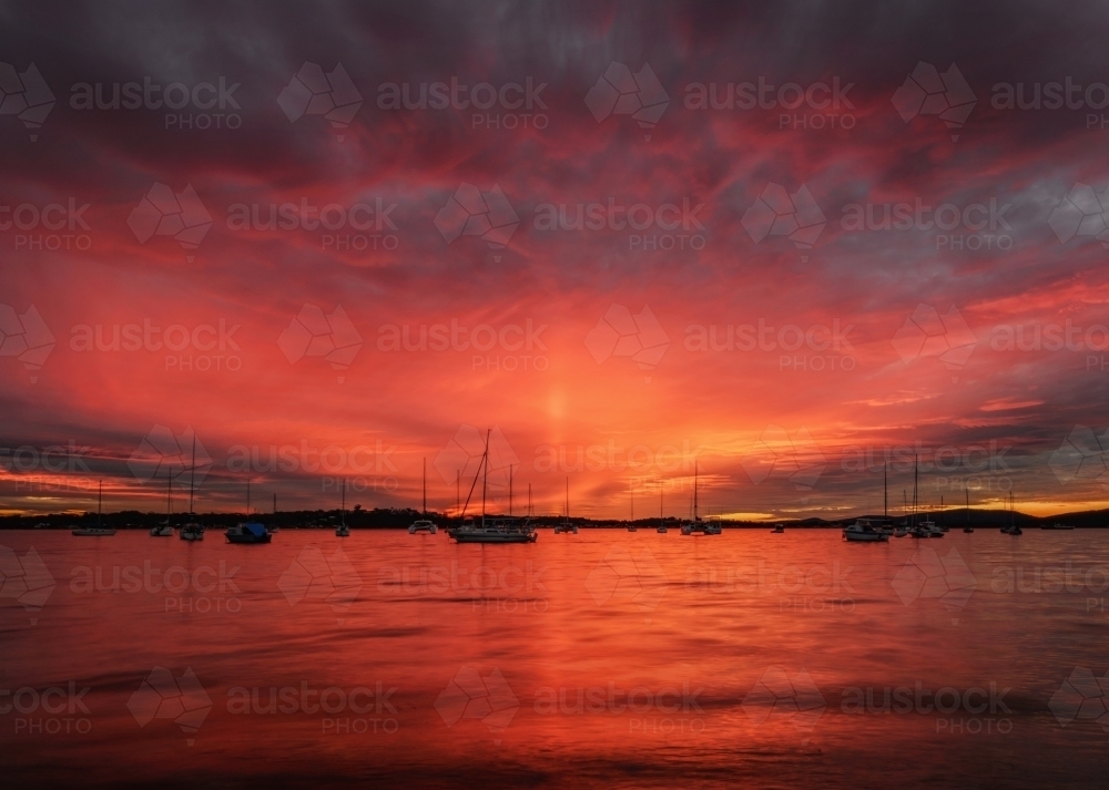 Dramatic red sunset behind yachts moored at Roy Wood Reserve, Port Stephens - Australian Stock Image