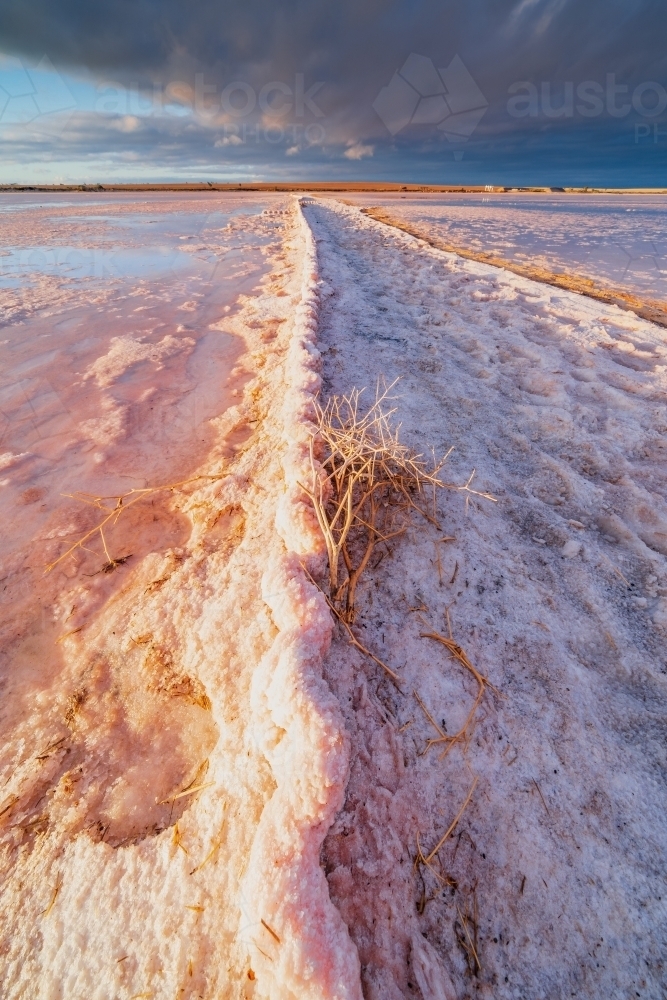 Dramatic side lightning hitting a rusted corrugated fence buried in salt lake - Australian Stock Image