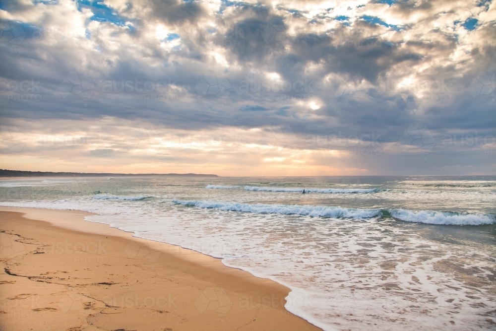 Dramatic sky over an empty beach at dawn - Australian Stock Image