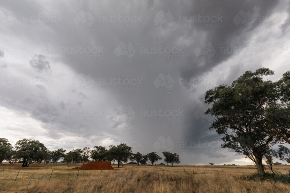 Image of Dramatic storm clouds gather over a dry, rural Australian ...