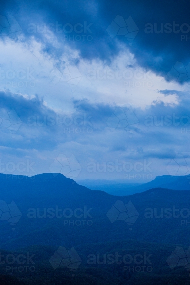 Image of Dramatic stormy sky over layered blue mountains at nightfall ...