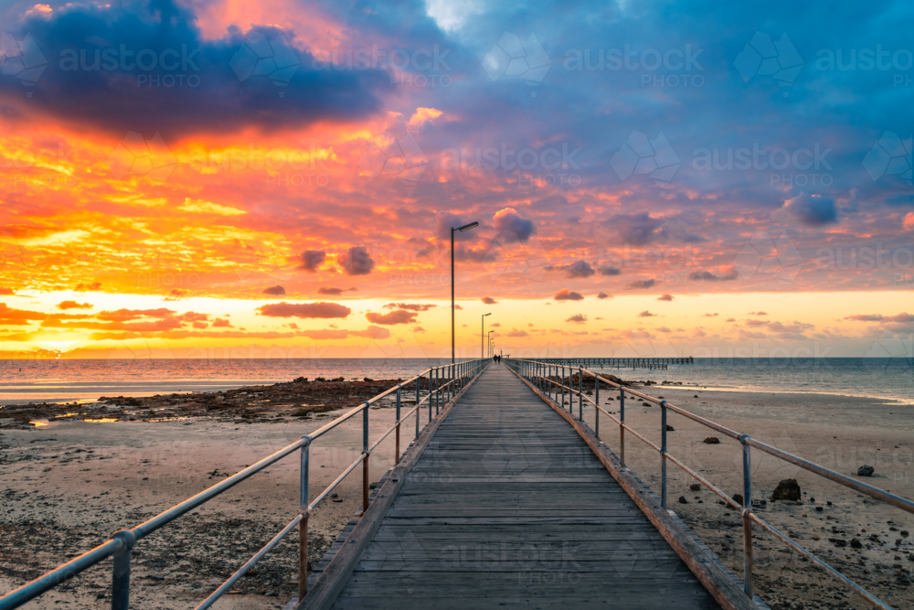 Dramatic sunset above Moonta Bay Jetty with people walking along,  Copper Coast, Yorke Peninsula - Australian Stock Image